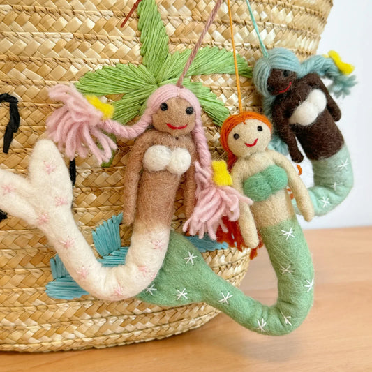 Handmade wool felt mermaid bag charms styled on a woven basket