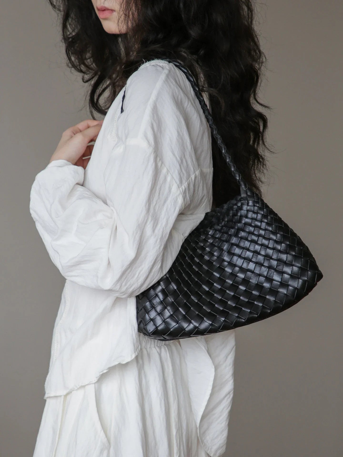 Black woven leather shoulder bag styled under the arm