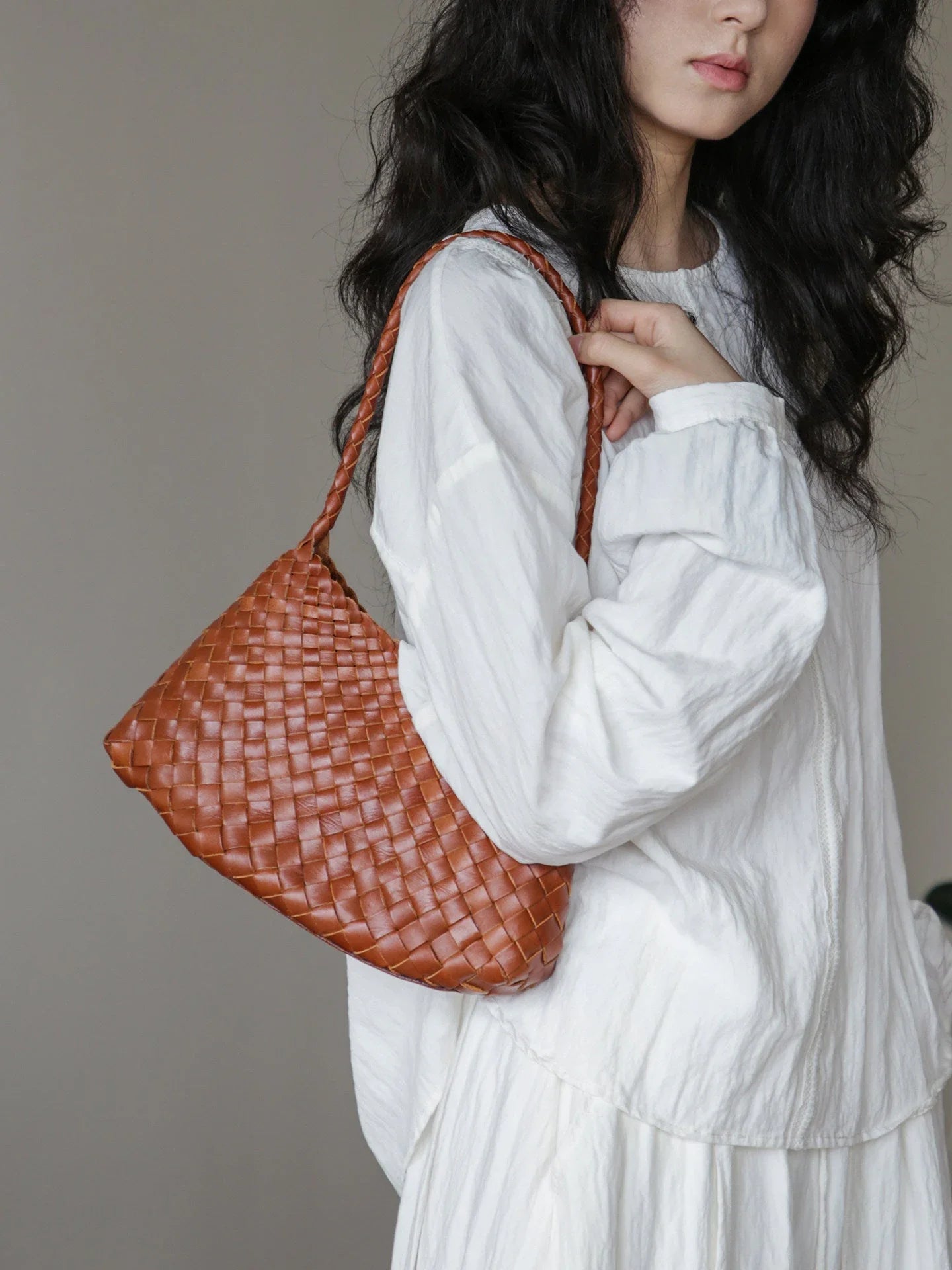 Brown vegetable-tanned woven leather shoulder bag styled under the arm
