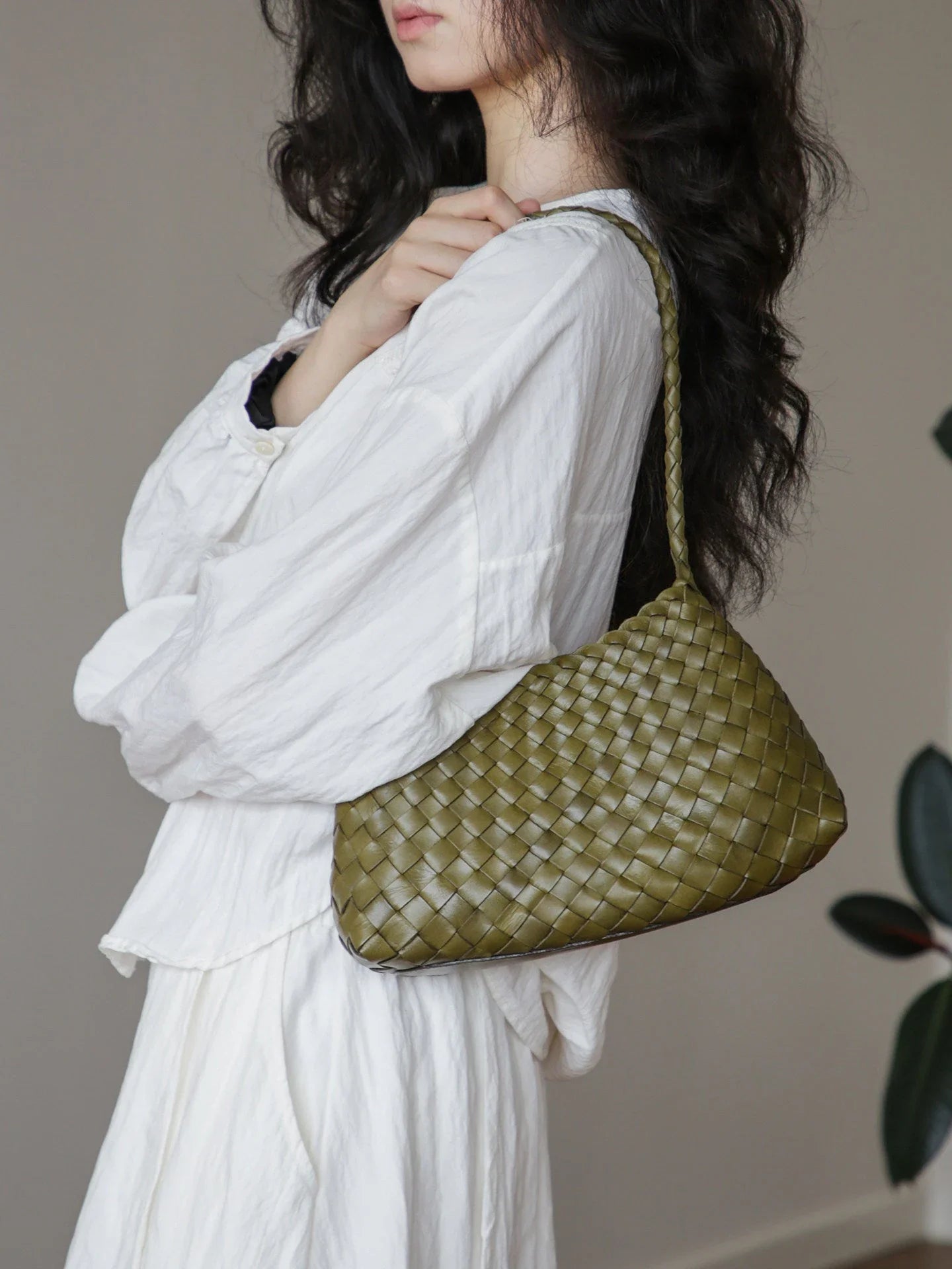 Olive green woven leather shoulder bag styled on the shoulder