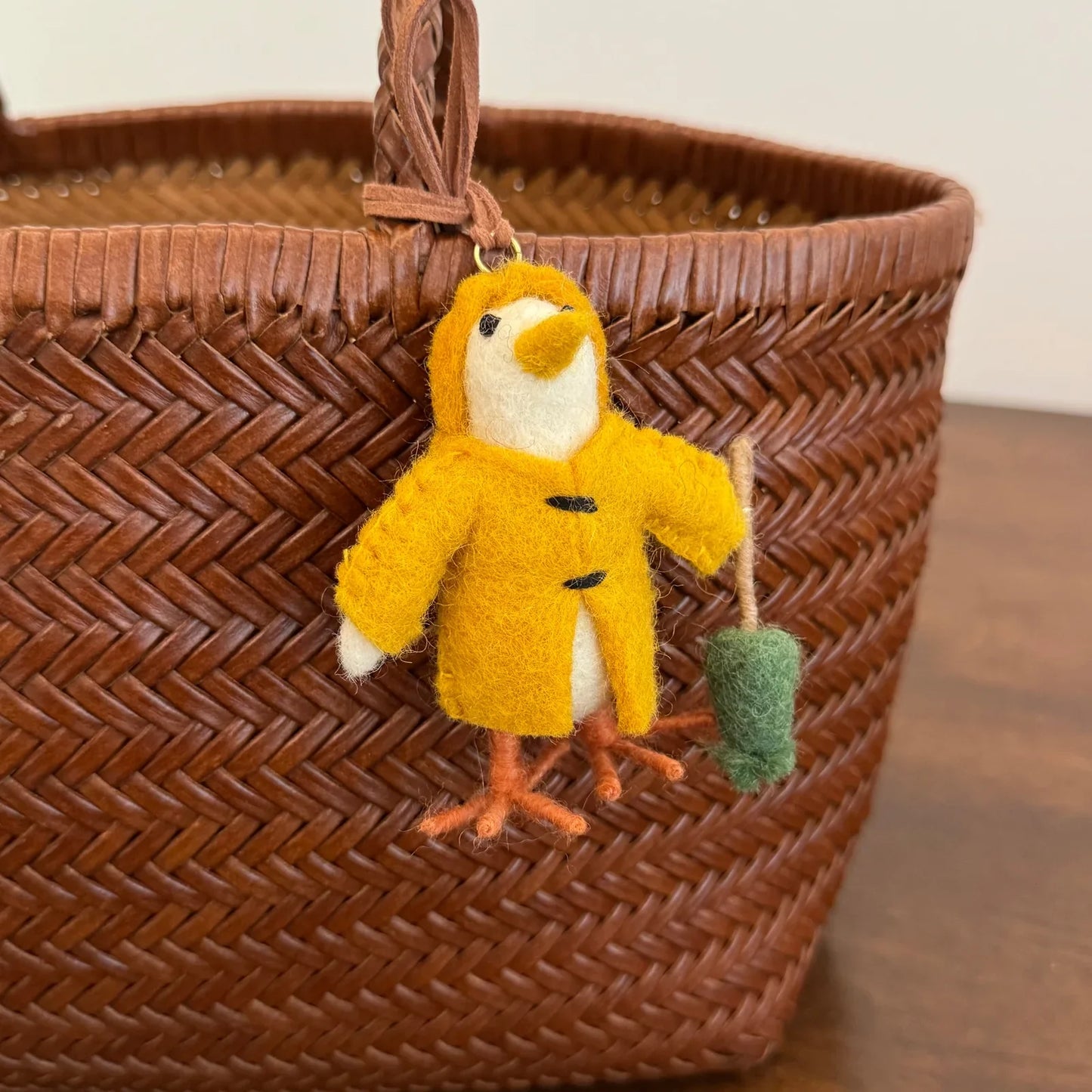 Close detail of yellow wool felt chick charm on woven bag